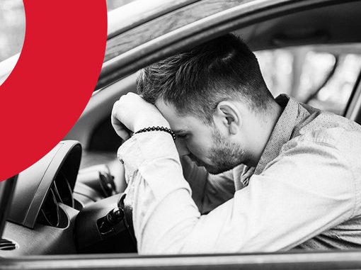 Capa de artigo multa RENAINF | DOK Despachante | Descrição: jovem homem branco debruçado sobre volante de carro em postura frustrada.