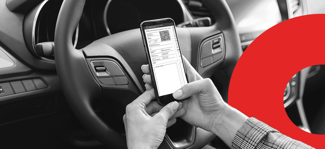 capa artigo atpv-e | DOK Despachante | Descrição: duas mãos seguram um celular, na tela do aparelho é possível ver o documento digital do carro; ao fundo, o volante e painel do veículo.