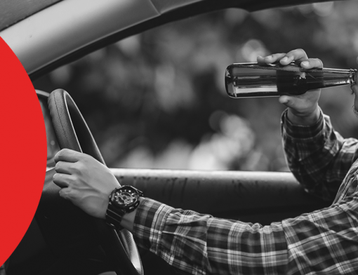 Capa de artigo: multa por dirigir embriagado | DOK Despachante. Descrição: imagem de um motorista dentro do carro, com uma garrafa de cerveja em uma mão levando até a boca, enquanto a outra mão repousa sobre o volante.