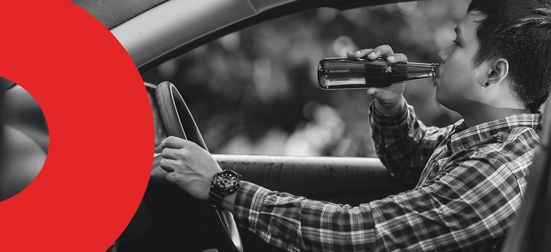 Capa de artigo: multa por dirigir embriagado | DOK Despachante. Descrição: imagem de um motorista dentro do carro, com uma garrafa de cerveja em uma mão levando até a boca, enquanto a outra mão repousa sobre o volante.