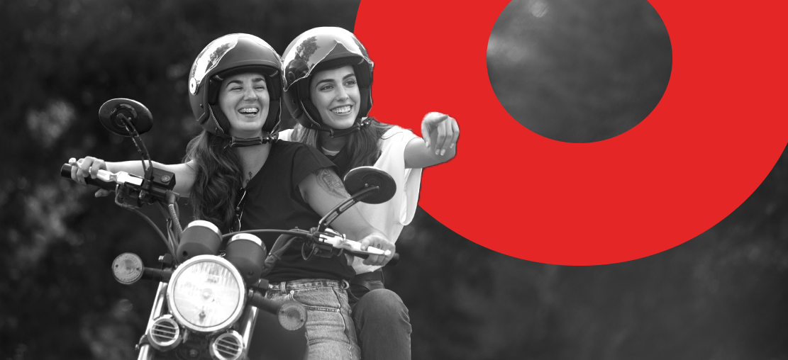 Capa do artigo modelos de moto | DOK Despachante | Descrição: duas mulheres em cima de uma moto, a que está na garupa aponta para o horizonte, ambas sorriem e usam capacete.