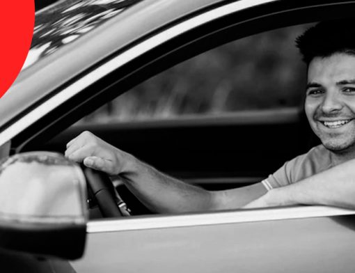 Capa de artigo Bradesco Seguros - DOK Despachante; Descrição: foto em preto e branco, jovem motorista homem e branco sorri ao segurar volante.