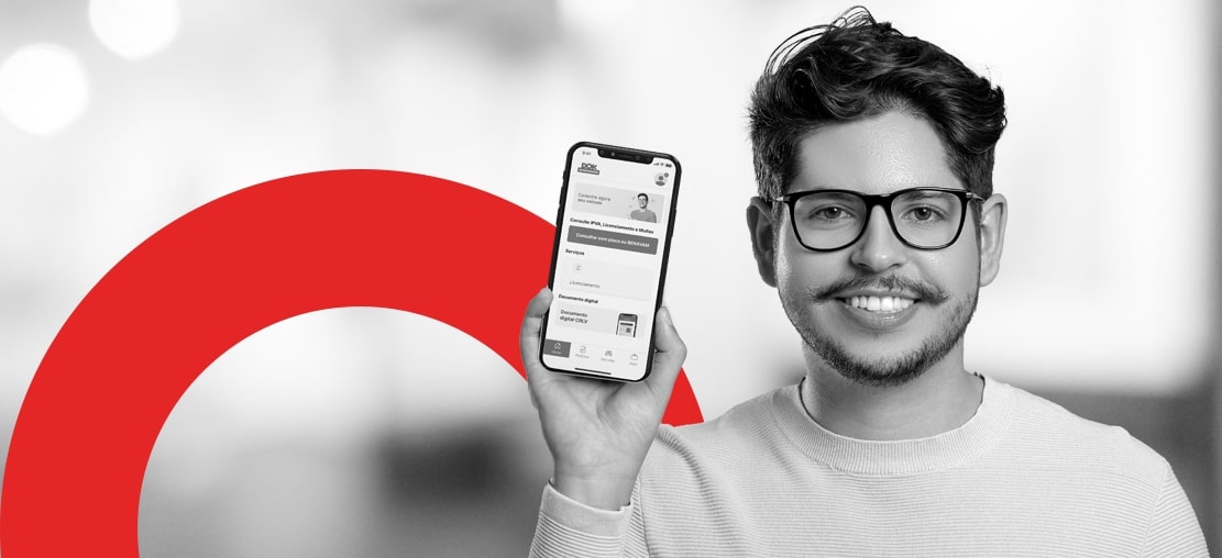 capa do artigo sobre do App DOK Despachante | Descrição: homem jovem branco, com barba e bigode, usa óculos e segura um celular ao lado do rosto olhando para a câmera; a foto está em preto e branco.